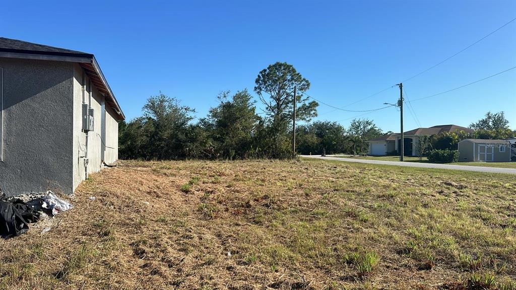 A side view of a house exterior next to an empty, grassy residential lot — 13009 RIDGELY CIRCLE, PORT CHARLOTTE, FL
