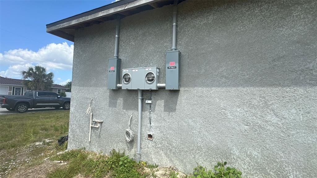 An exterior view of a residential building showing two electrical meters and disconnect boxes — 13009 RIDGELY CIRCLE, PORT CHARLOTTE, FL