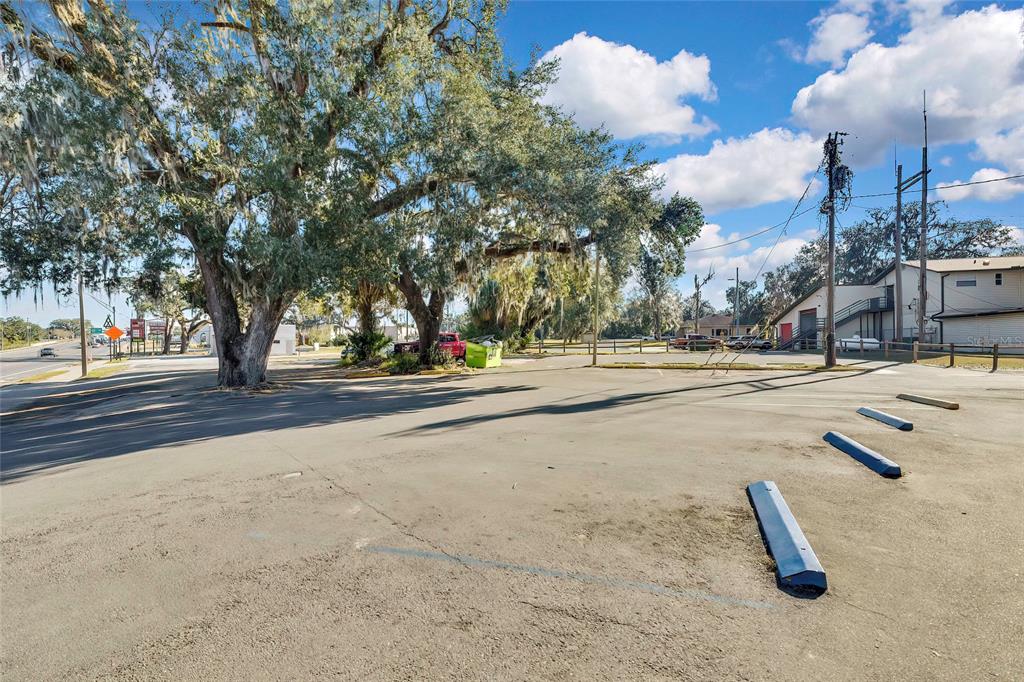 An outdoor parking lot features several concrete wheel stops and large trees under a blue sky — 104 US HIGHWAY 41 S, INVERNESS, FL