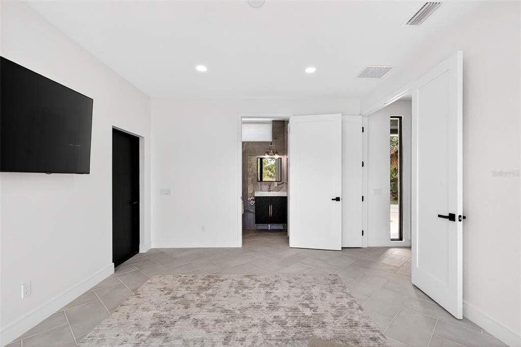 A modern bedroom with white walls, gray tile flooring, and black interior doors — 2946 N OCEAN SHORE BOULEVARD, FLAGLER BEACH, FL