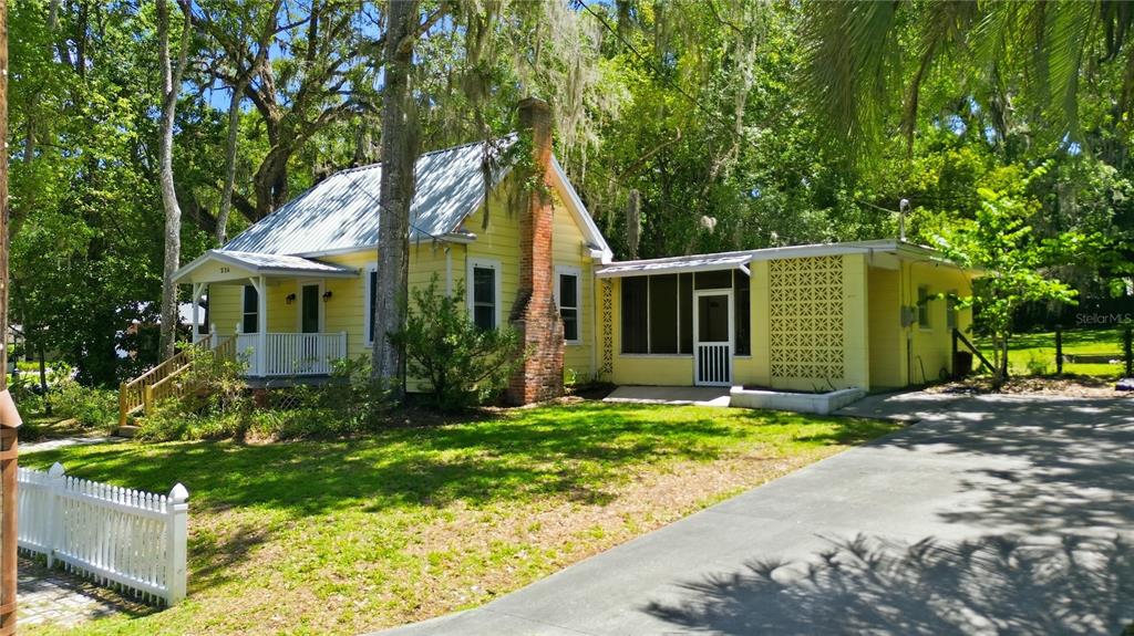 A yellow cottage with a metal roof, brick chimney, and a screened-in porch — 236 PRYOR STREET, BROOKSVILLE, FL