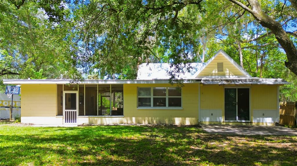 The exterior of a yellow house features a screened-in porch and a sliding glass door — 236 PRYOR STREET, BROOKSVILLE, FL