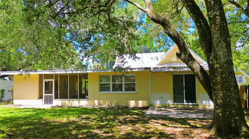A yellow house with a screened-in porch, sliding glass doors, and a large oak tree — 236 PRYOR STREET, BROOKSVILLE, FL