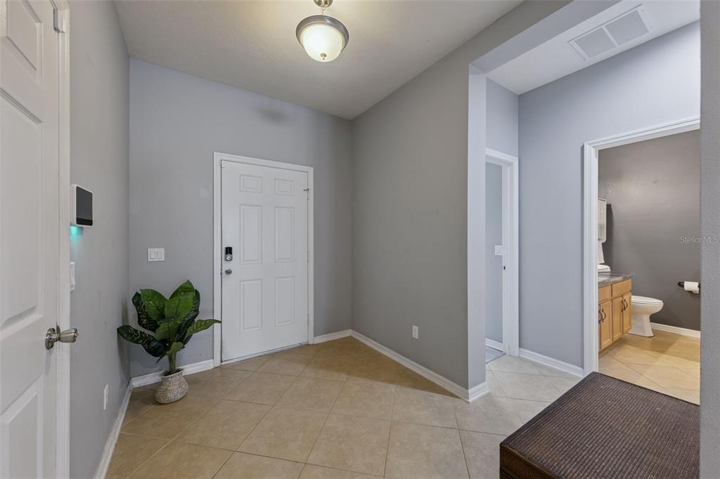 A tiled entryway features gray walls, a white front door, and a nearby bathroom — 3809 ENCHANTMENT LANE, ST CLOUD, FL