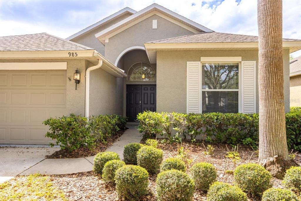 A single-story house with a beige stucco exterior, a garage, and a landscaped front yard — 985 RIDGEMOUNT PLACE, LAKE MARY, FL