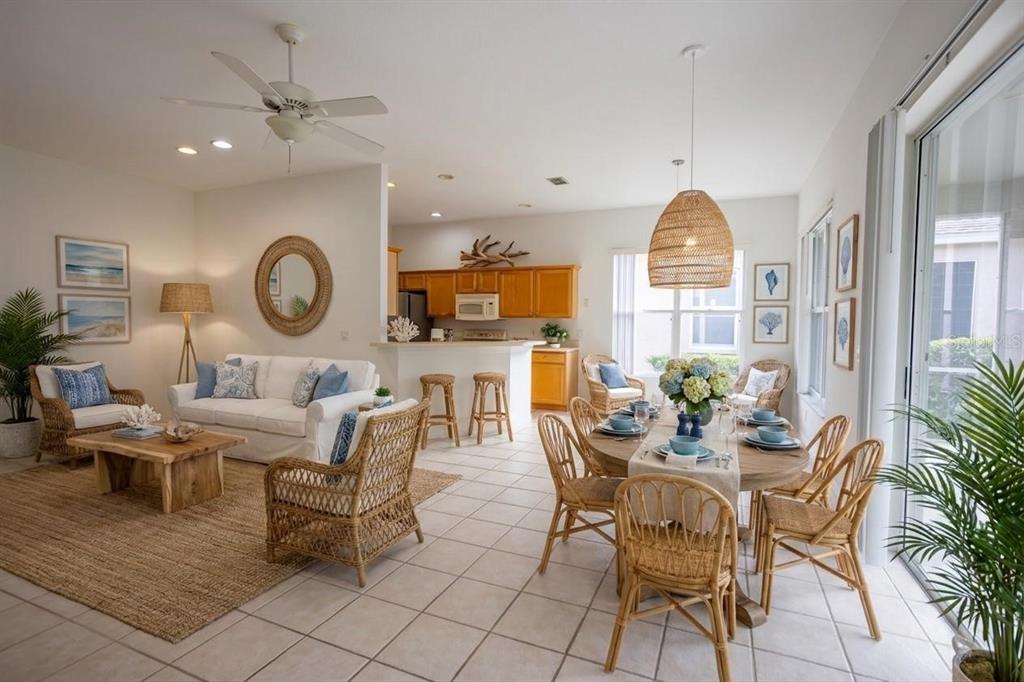 An open-concept living and dining area features wicker furniture, a white sofa, and tile flooring — 985 RIDGEMOUNT PLACE, LAKE MARY, FL