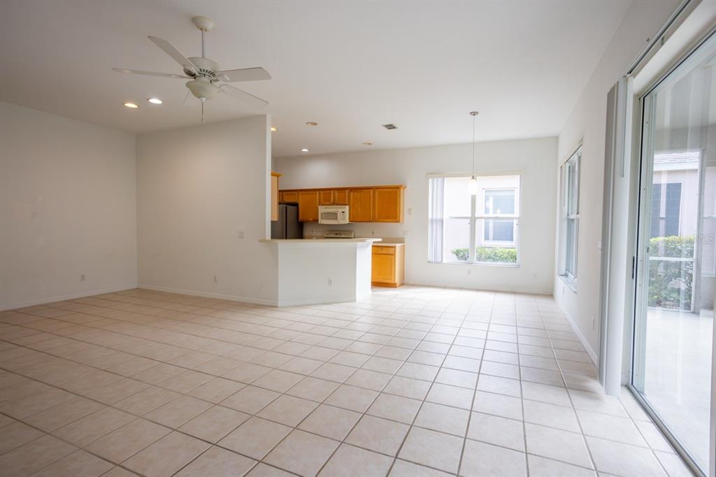 An open-concept living and dining area features light tile flooring and a kitchen with cabinets — 985 RIDGEMOUNT PLACE, LAKE MARY, FL
