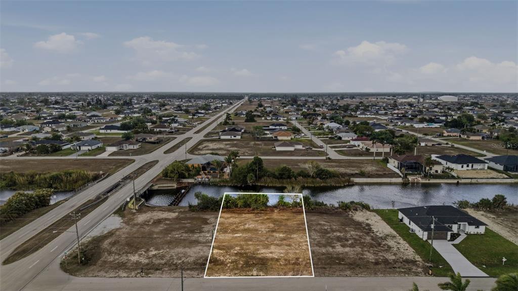 An aerial view shows a vacant rectangular lot bordering a canal in a residential neighborhood — 1525 NW 17TH STREET, CAPE CORAL, FL