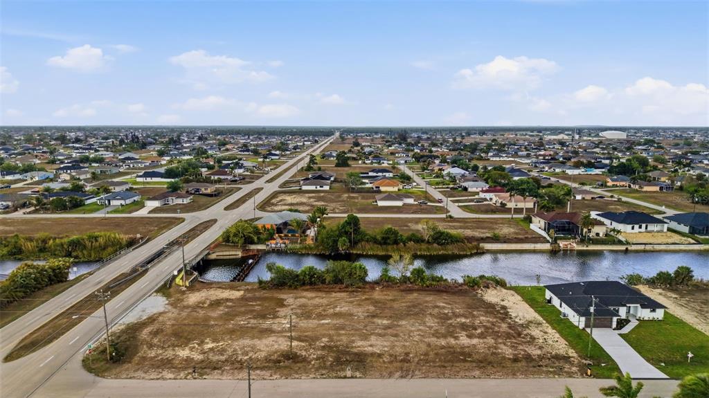 An aerial view shows a vacant residential lot next to a canal and a road — 1525 NW 17TH STREET, CAPE CORAL, FL