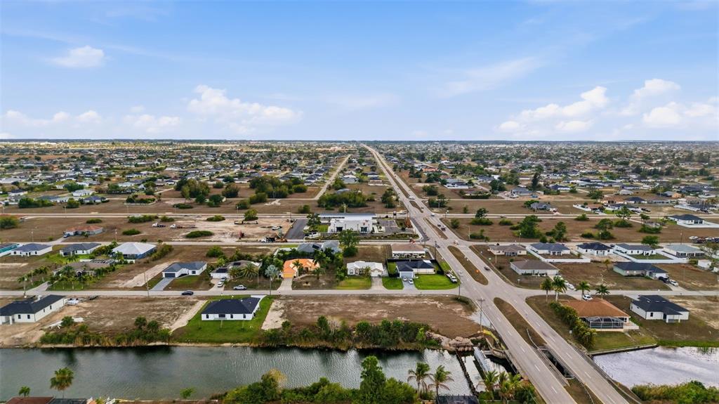 An aerial view shows a suburban neighborhood with houses, a canal, and intersecting roads — 1525 NW 17TH STREET, CAPE CORAL, FL