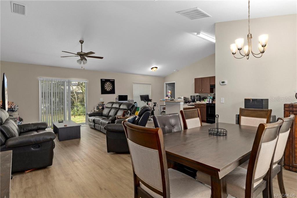 An open-concept living and dining area features wood-look flooring, vaulted ceilings, and a kitchen island — 3551 W BURGANDY DRIVE, CITRUS SPRINGS, FL