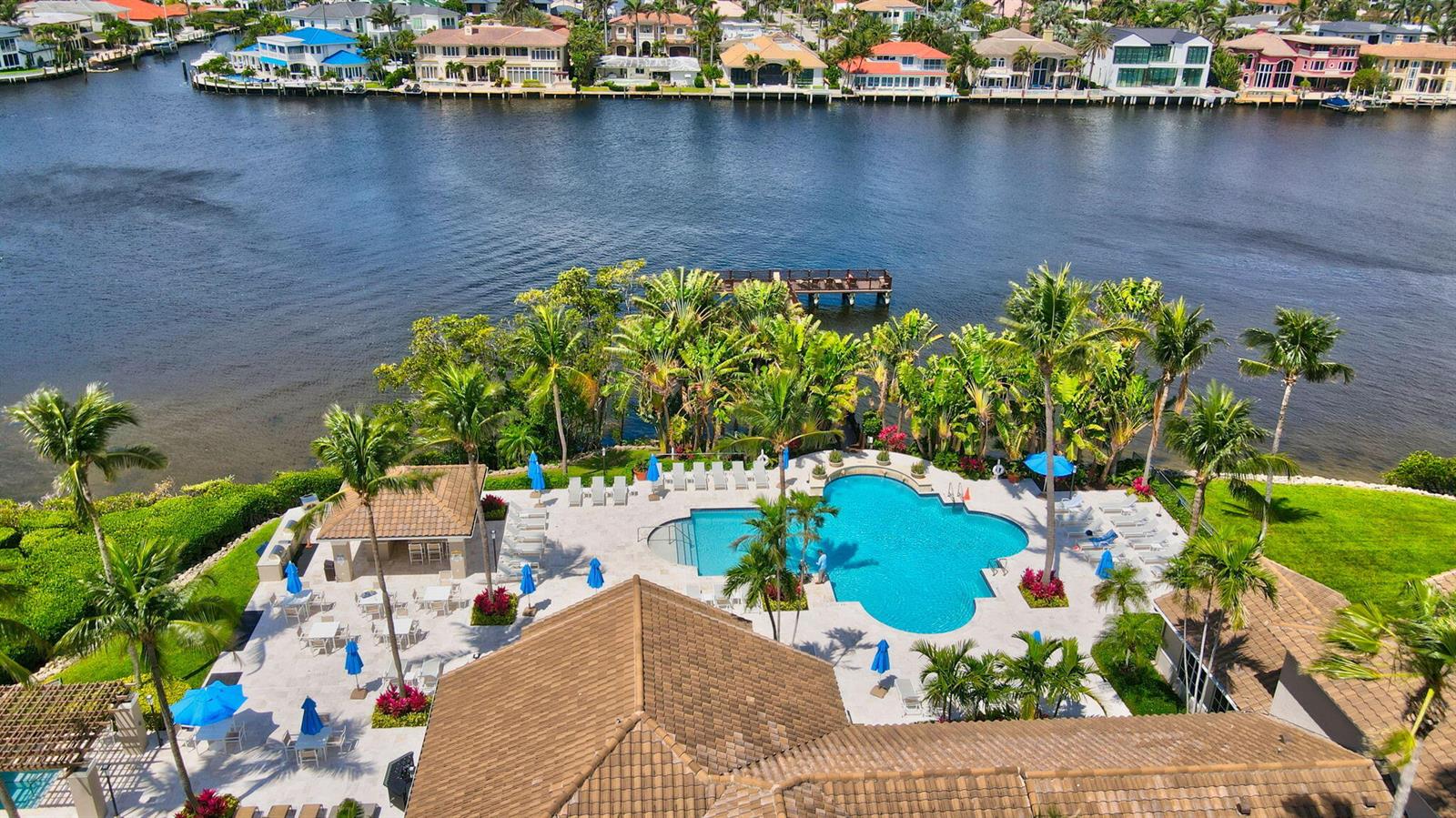 An aerial view of a swimming pool area with palm trees and a waterfront dock — 3594 S Ocean Boulevard # 302, Highland Beach FL 33487, HIGHLAND BEACH, FL