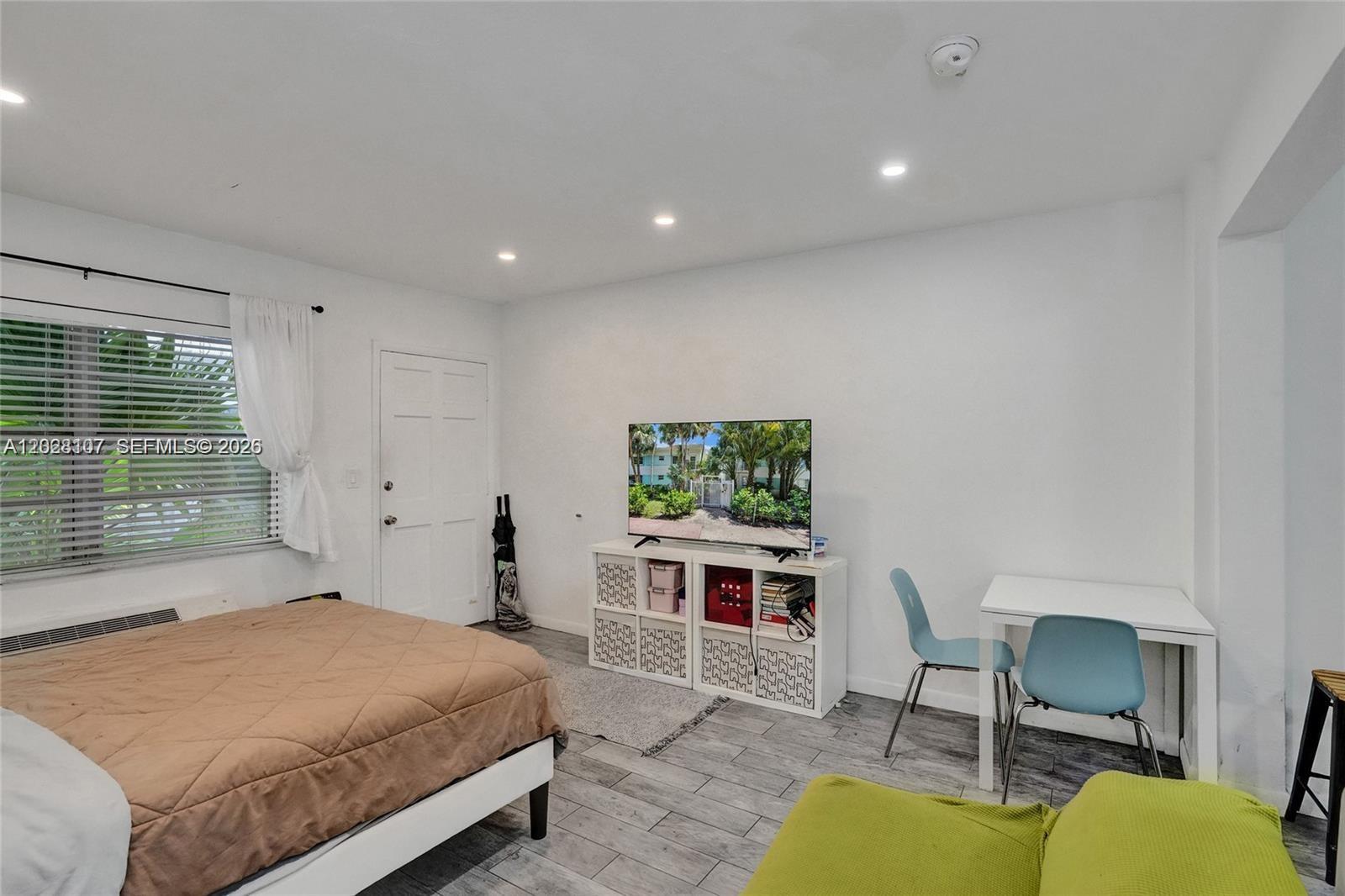 A bedroom features a bed, a television on a storage unit, and a small desk — 911 Meridian Ave # 104, Miami Beach FL 33139, MIAMI BEACH, FL