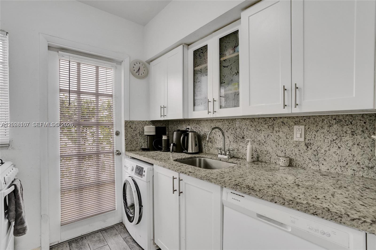 A kitchen features white cabinets, granite countertops, a stainless steel sink, and a built-in washer — 911 Meridian Ave # 104, Miami Beach FL 33139, MIAMI BEACH, FL