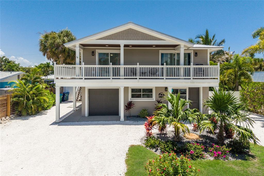 A two-story house with a white balcony, a garage, and a gravel driveway — 203 72ND STREET, HOLMES BEACH, FL