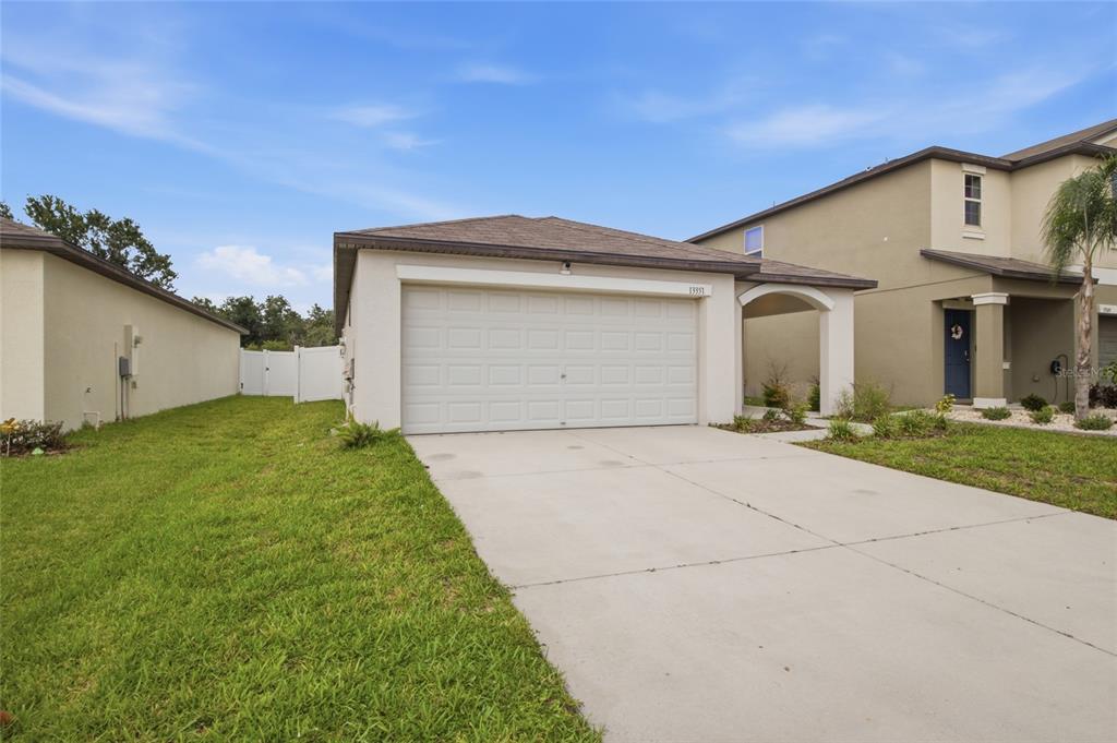 A single-story house with a white garage door, a concrete driveway, and a side entrance — 13351 WILLOW BLUESTAR LOOP, RIVERVIEW, FL