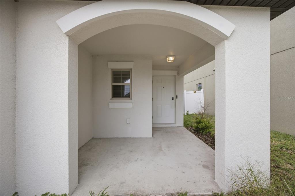 A covered concrete entryway features a white front door and a single window — 13351 WILLOW BLUESTAR LOOP, RIVERVIEW, FL