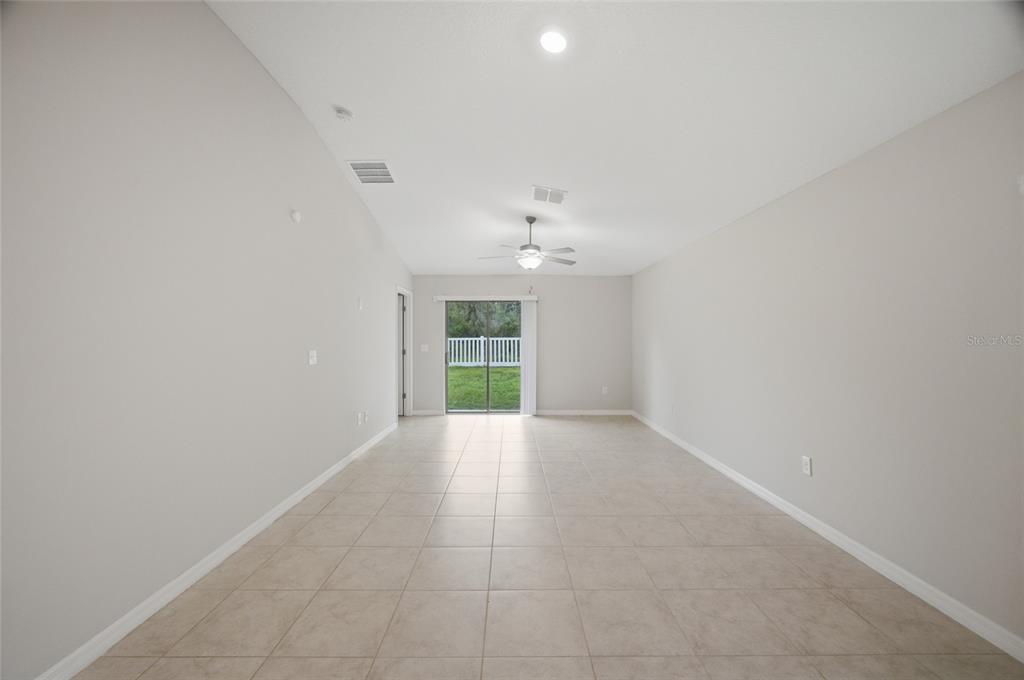 An empty room with light-colored tile flooring, gray walls, a ceiling fan, and sliding doors — 13351 WILLOW BLUESTAR LOOP, RIVERVIEW, FL