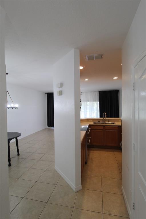 A view from a hallway looking into a tiled kitchen and an adjacent dining area — 10963 SAVANNAH WOOD DRIVE UNIT 160, ORLANDO, FL