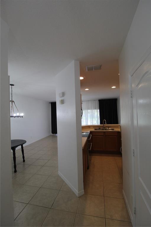 A view from a hallway looking into a tiled kitchen and an adjacent dining area — 10963 SAVANNAH WOOD DRIVE UNIT 160, ORLANDO, FL