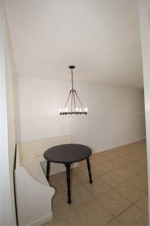 A dining nook features a white corner bench, a round black table, and a chandelier — 10963 SAVANNAH WOOD DRIVE UNIT 160, ORLANDO, FL