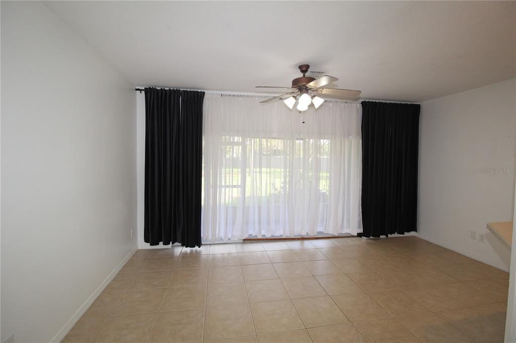 A room with tan tile flooring, a ceiling fan, and sliding glass doors with curtains — 10963 SAVANNAH WOOD DRIVE UNIT 160, ORLANDO, FL