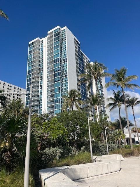 A tall white residential high-rise building stands behind palm trees and a concrete walkway — 2655 Collins Ave # 1404, Miami Beach FL 33140, MIAMI BEACH, FL