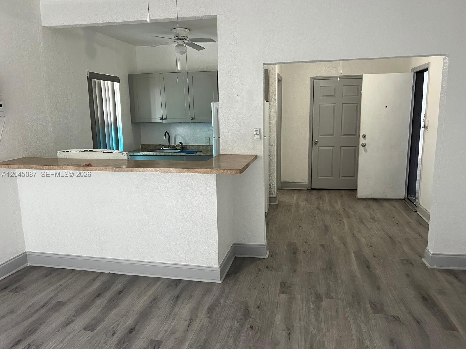 A kitchen with gray cabinets and a breakfast bar overlooks a room with wood-look flooring — 1322 SW 7th St # 8, Miami FL 33135, MIAMI, FL