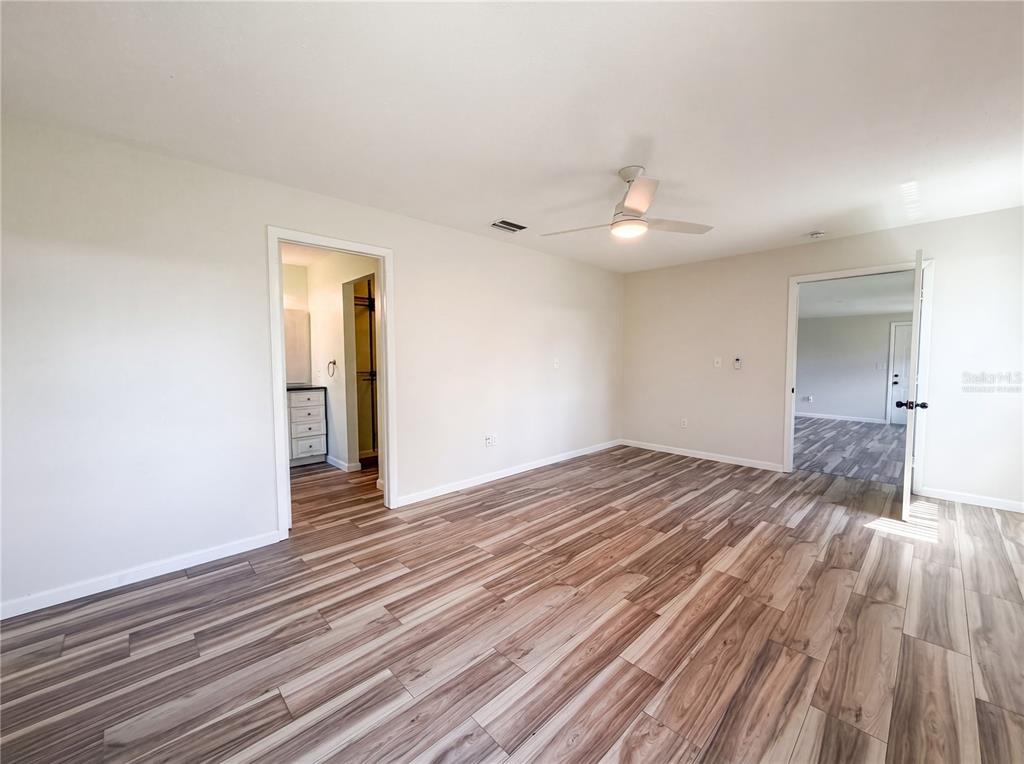 An empty room features light-colored walls, a ceiling fan, and wood-look flooring — 3260 PINETREE STREET, PORT CHARLOTTE, FL