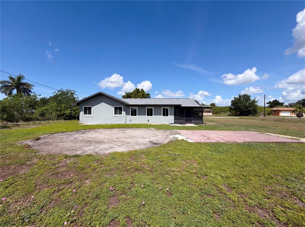The exterior of a gray, single-story house features a concrete pad and a brick patio — 3260 PINETREE STREET, PORT CHARLOTTE, FL