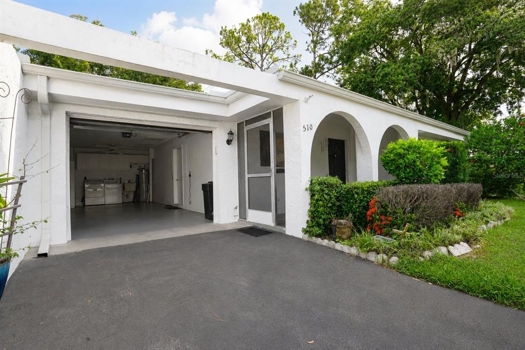 A white house exterior features an open garage, arched entryway, and a paved driveway — 510 PALMER CIRCLE, PALM HARBOR, FL