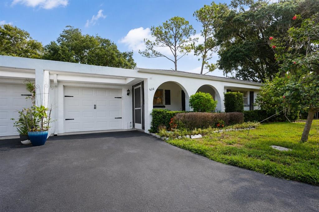 A white single-story house with a garage, arched entryway, and a paved driveway — 510 PALMER CIRCLE, PALM HARBOR, FL