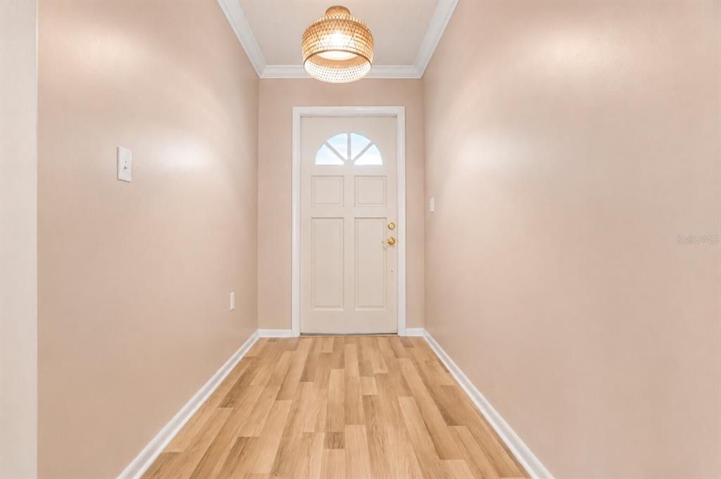 A bright entryway features light-colored walls, wood-look flooring, and a central woven pendant light — 510 PALMER CIRCLE, PALM HARBOR, FL