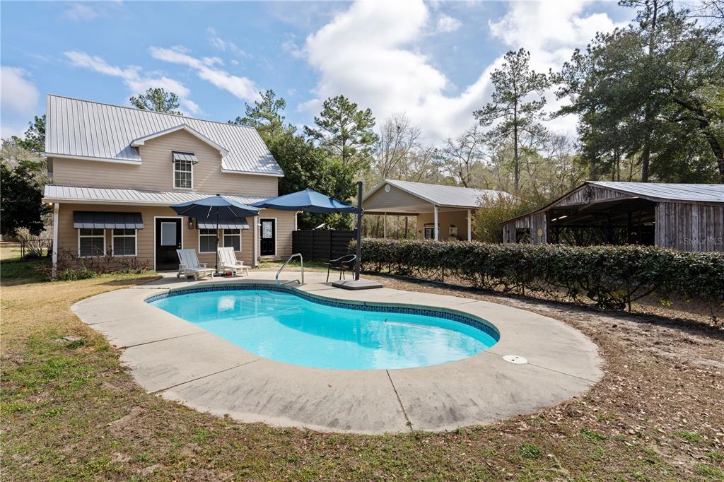 A two-story house with a metal roof features a backyard swimming pool and outbuildings — 210 TUCKER SPRINGS ROAD, SOPCHOPPY, FL
