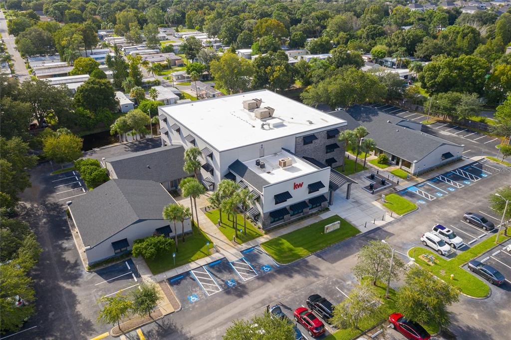An aerial view shows a multi-story commercial building with a parking lot and surrounding trees — 30522 US HIGHWAY 19 N UNIT 105, PALM HARBOR, FL