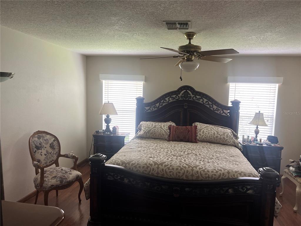 A bedroom features a large dark wood bed frame, two nightstands, and a floral chair — 1815 AMERICUS MINOR DRIVE, WINTER GARDEN, FL