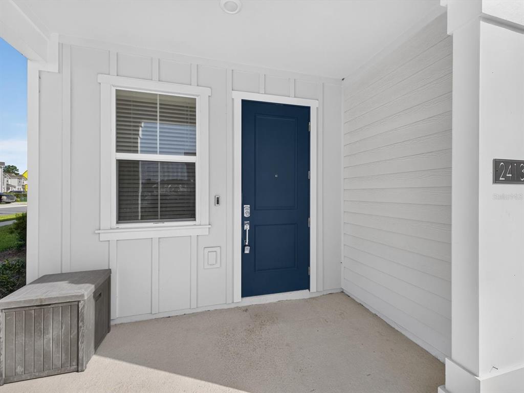 A blue front door is set into a white exterior wall with a window — 2413 BROOK MARSH LOOP, KISSIMMEE, FL