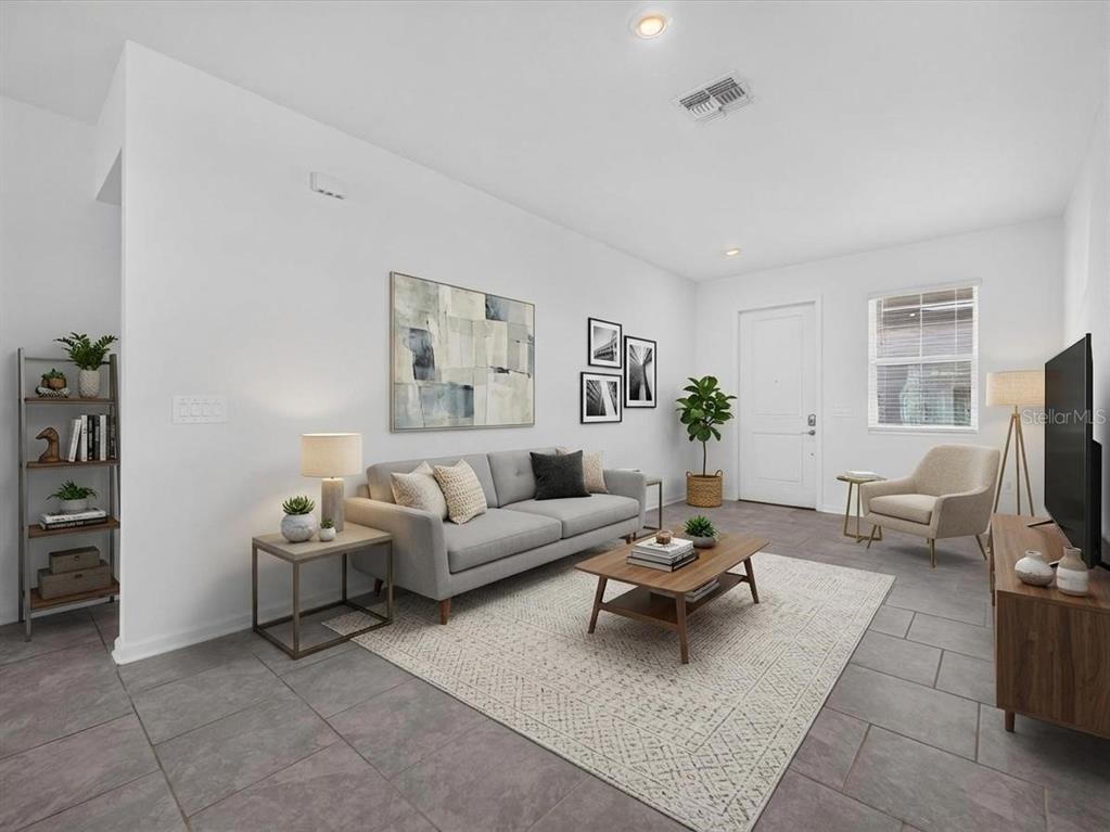 A living room features gray tile flooring, a light gray sofa, and a wooden coffee table — 2413 BROOK MARSH LOOP, KISSIMMEE, FL