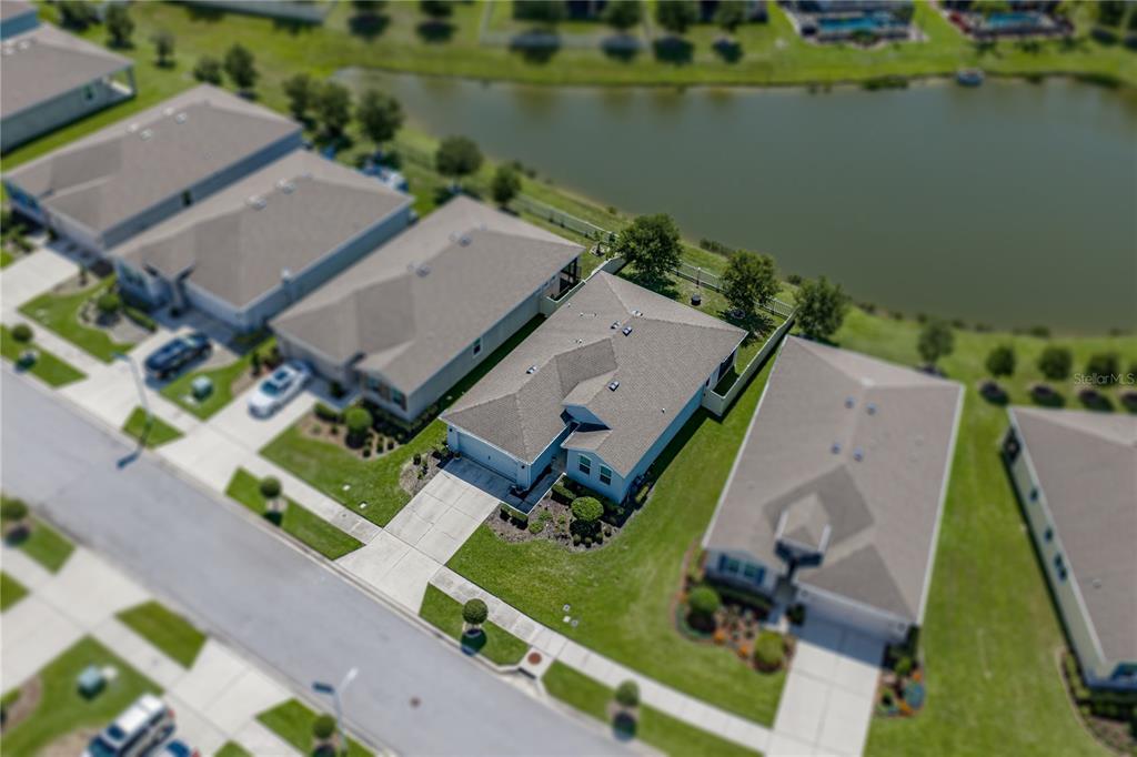 An aerial view shows a suburban house with a gray roof near a pond — 31785 TANSY BEND, WESLEY CHAPEL, FL
