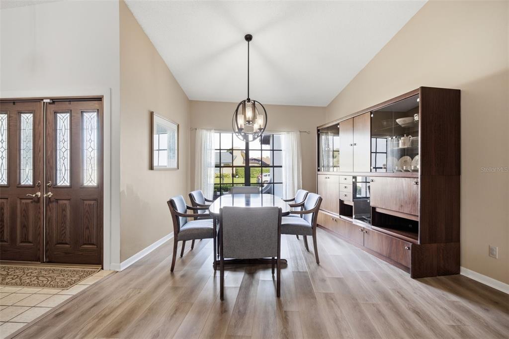 A dining room features a wooden hutch, a central chandelier, and a table with six chairs — 13707 ATTLEY PLACE, TAMPA, FL