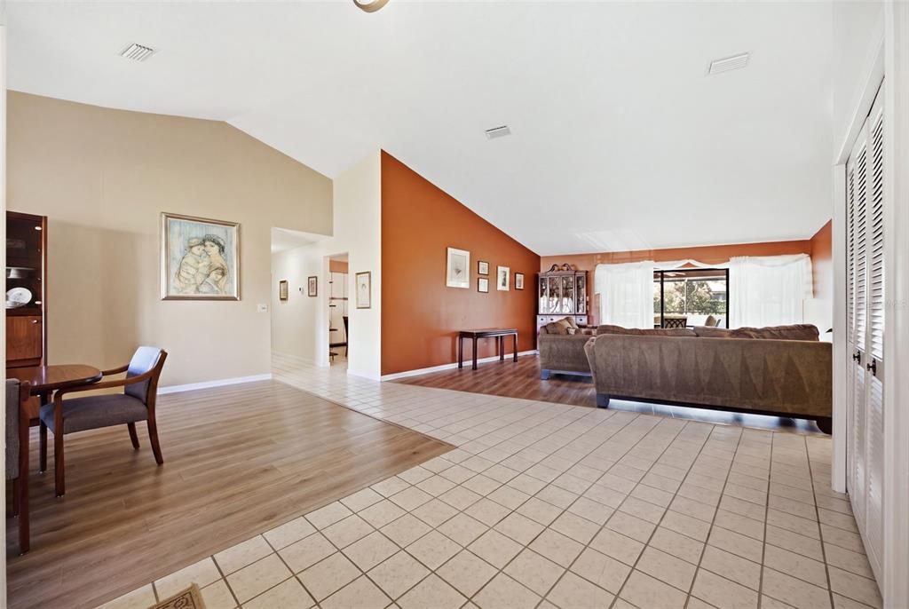A living and dining area features vaulted ceilings, tile and wood flooring, and orange walls — 13707 ATTLEY PLACE, TAMPA, FL