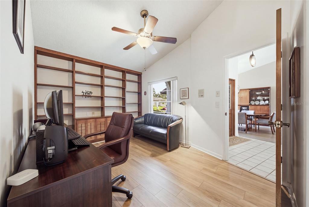 A home office features wood flooring, built-in bookshelves, a desk, a sofa, and a ceiling fan — 13707 ATTLEY PLACE, TAMPA, FL
