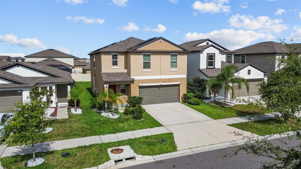 A two-story suburban house with a tan exterior, a two-car garage, and a front lawn — 16671 KINGMAN REEF STREET, WIMAUMA, FL
