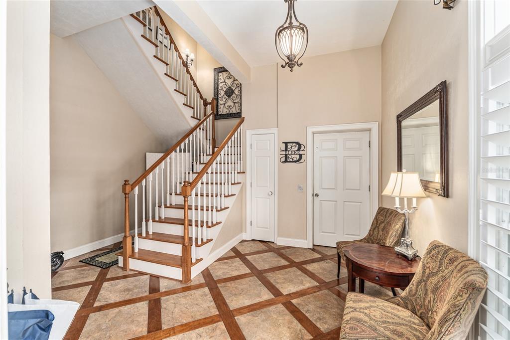 A foyer features a wooden staircase, tile flooring with wood inlays, and two patterned chairs — 5015 SW 91 TERRACE, GAINESVILLE, FL