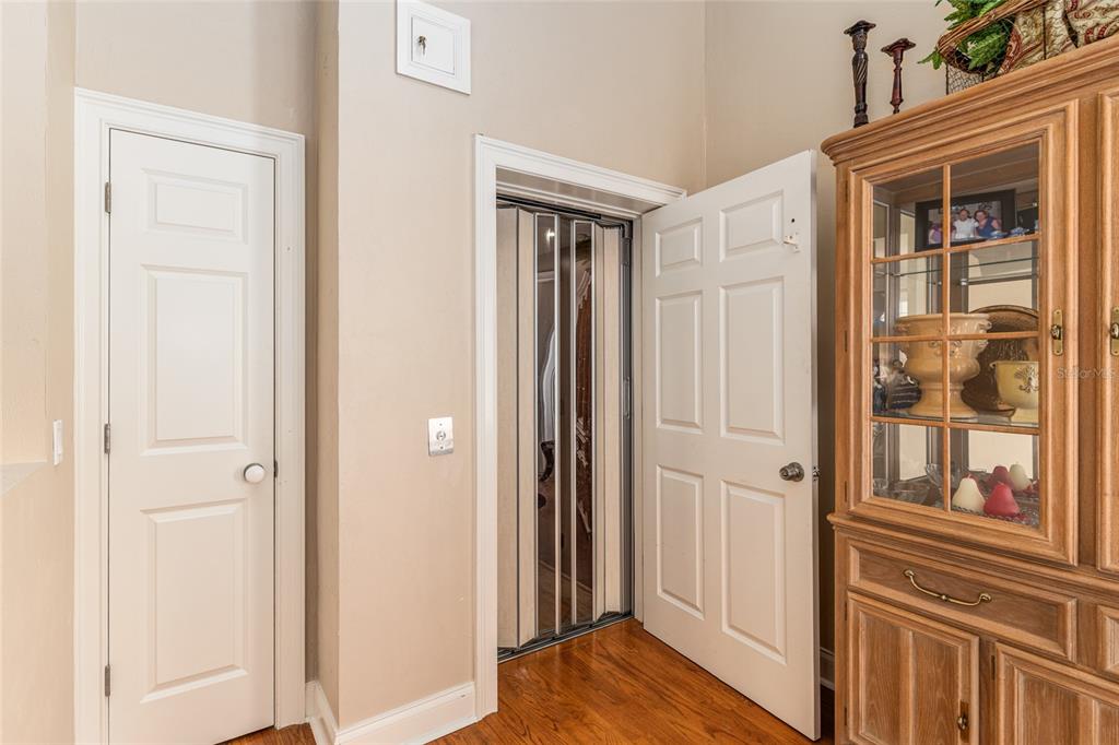 A room with hardwood floors, a closed door, and an open door revealing an elevator — 5015 SW 91 TERRACE, GAINESVILLE, FL