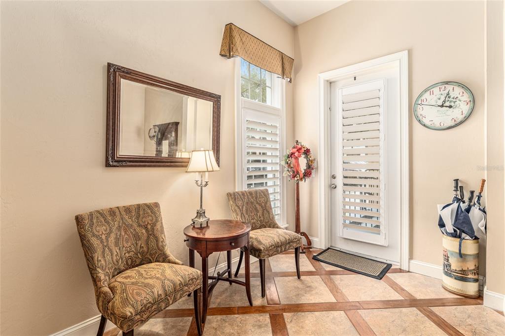 An entryway features two patterned chairs, a small round table, a mirror, and a door — 5015 SW 91 TERRACE, GAINESVILLE, FL