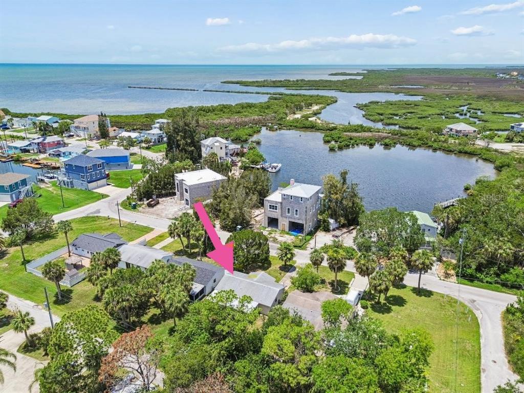 An aerial view shows a single-story house with a gray roof in a coastal neighborhood — 6826 DRIFTWOOD DRIVE, HUDSON, FL