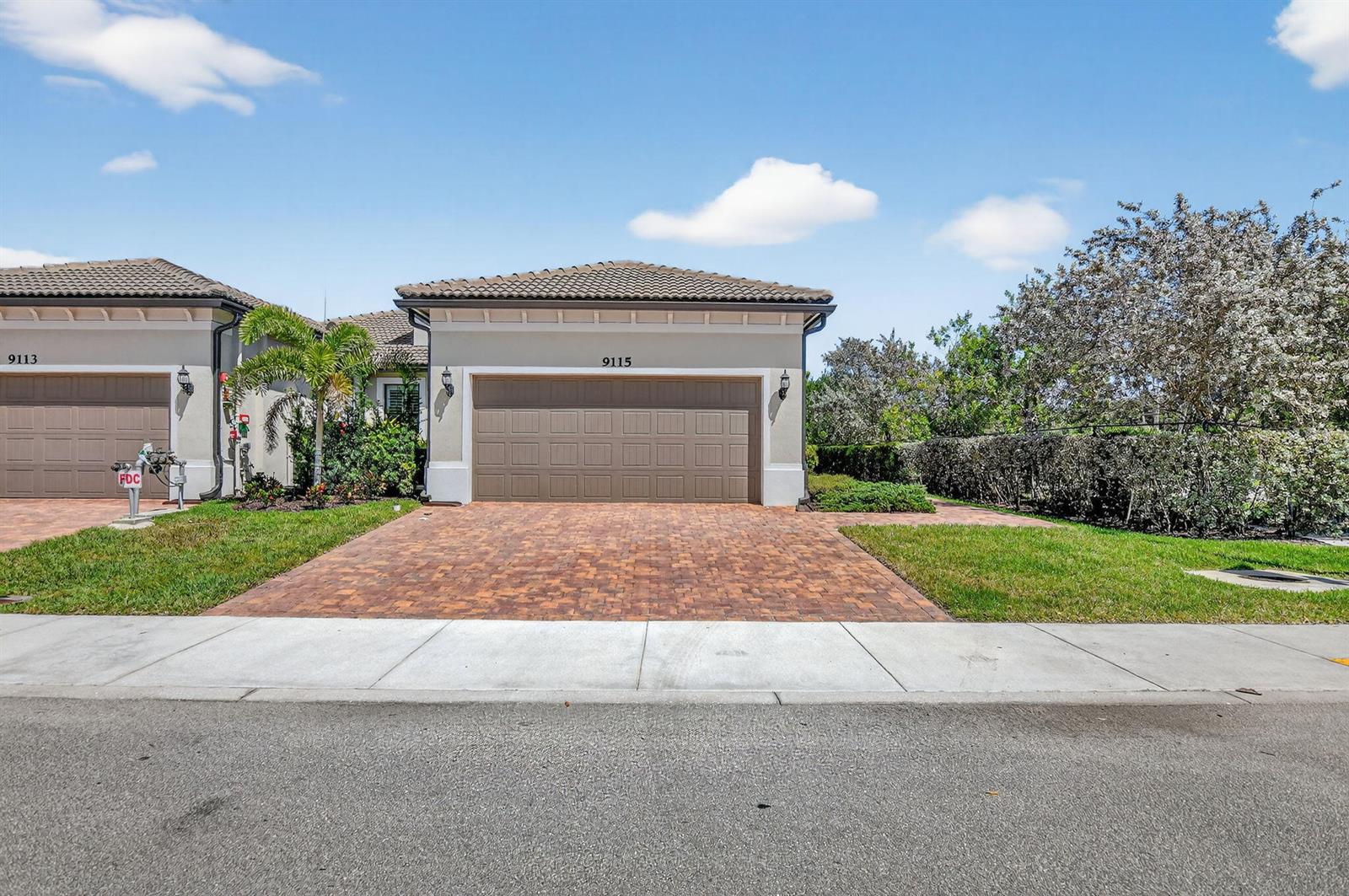 A single-story house exterior features a brown garage door, brick driveway, and a tiled roof — 9115 Passiflora Way, Boca Raton FL 33428, BOCA RATON, FL