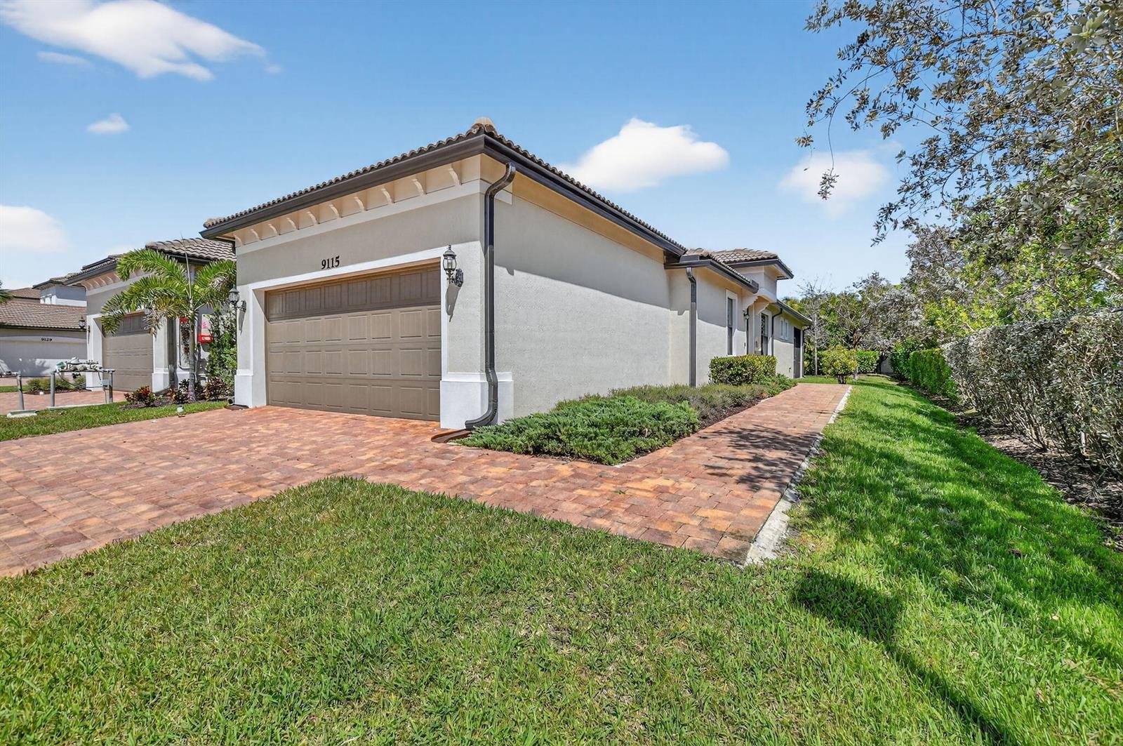 A beige single-story house features a brown garage door, a tiled roof, and a brick driveway — 9115 Passiflora Way, Boca Raton FL 33428, BOCA RATON, FL