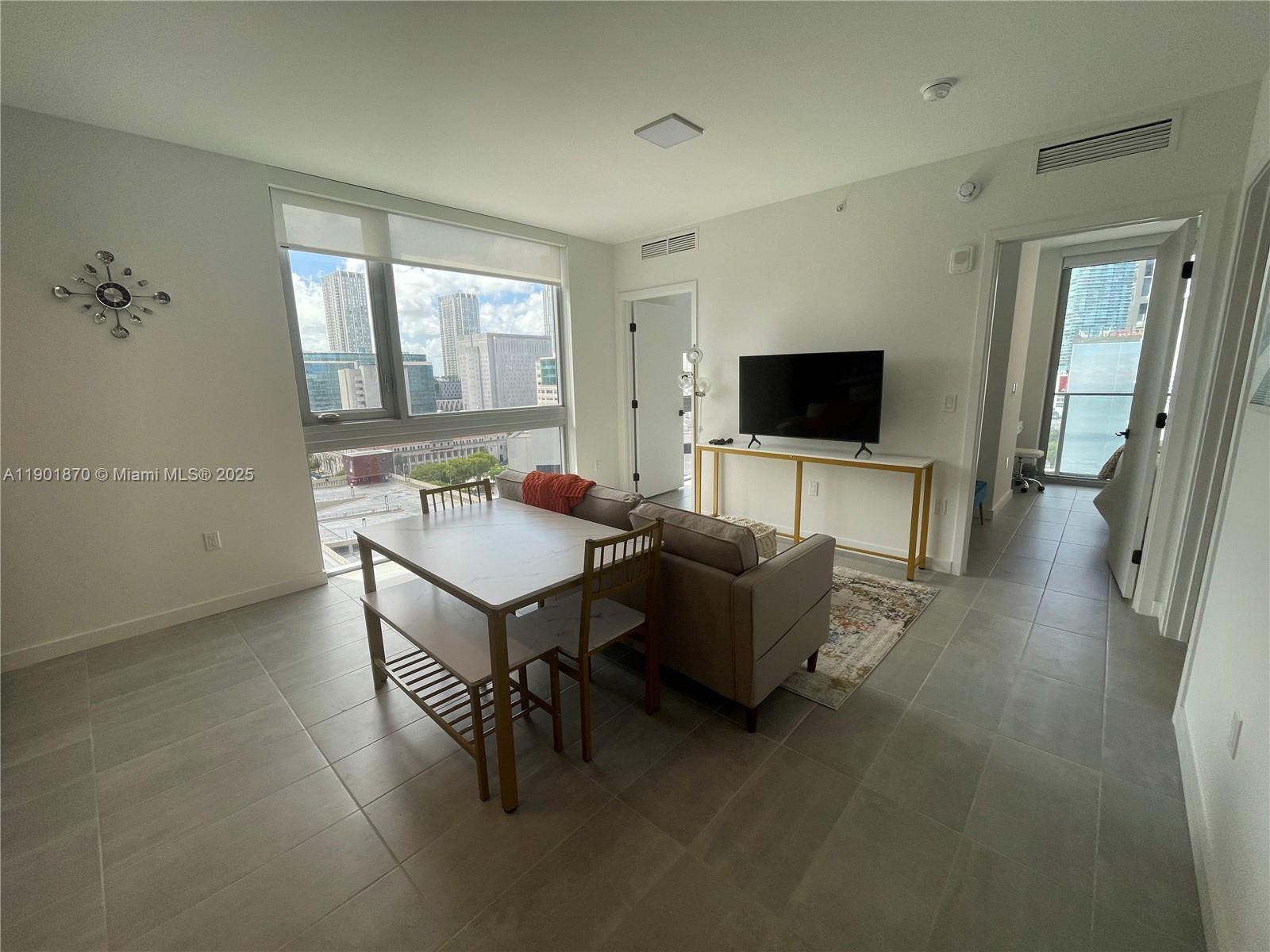 A living and dining area features tile floors, a sofa, a dining table, and city views — 227 NE 2nd St # 1606, Miami FL 33132, MIAMI, FL